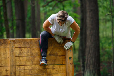 Full length of woman on tree trunk in forest