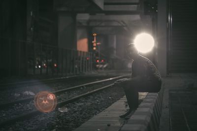 Side view of woman at railroad station at night