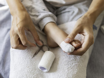 Mother bandages her child's big toe. close-up photo of kid's foot with bandaged finger. 