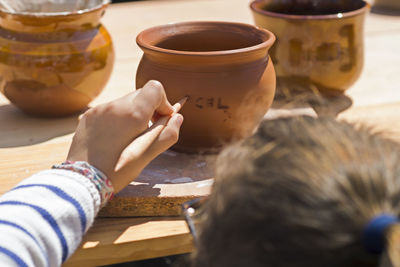 Close-up of girl writing on earthen bowl in market