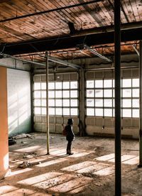 Young woman with backpack standing in abandoned room