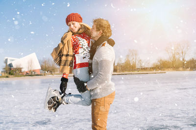 Couple embracing while standing on snow covered land