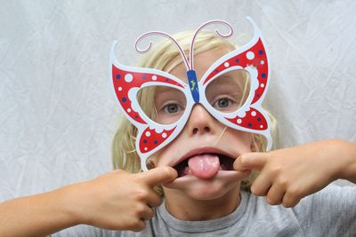 Close-up portrait of boy wearing eye mask while sticking out tongue