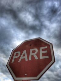 Close-up of signboard against cloudy sky