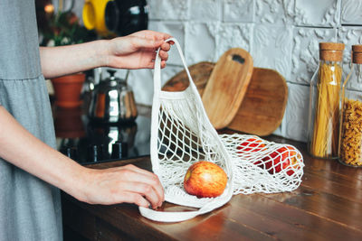 Midsection of woman with apples at table