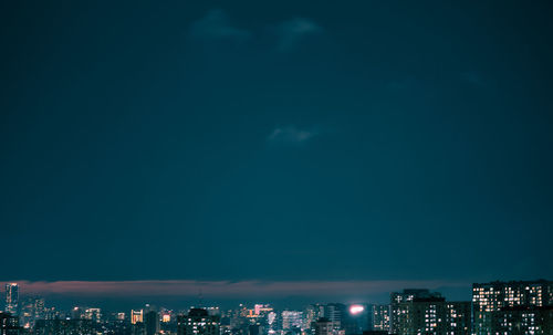 Illuminated buildings in city against sky at night