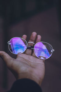 Close-up of human hand holding eyeglasses outdoors