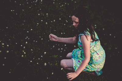 Close-up of girl picking flowers on field