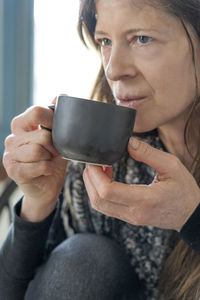 Close-up of thoughtful mature woman drinking coffee at home