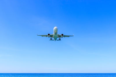 Airplane flying over sea against blue sky