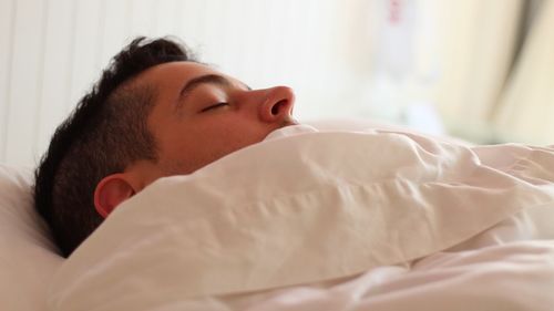 Close-up of young woman lying on bed at home