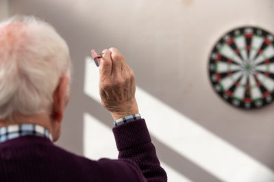 Rear view of man targeting board with dart at home