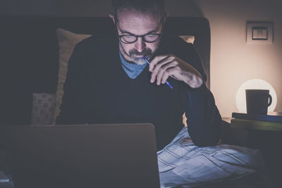 Man works with laptop lying on bed. male home working remote office sitting in bedroom use devices