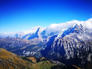 Scenic view of snowcapped mountains against blue sky