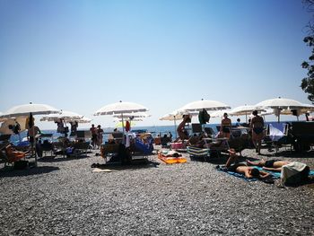 People at beach against clear sky