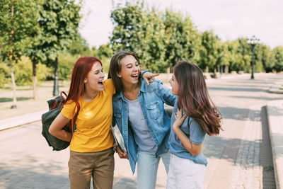 Schoolgirls walk along the park alley to school, talk and laugh. the concept of training