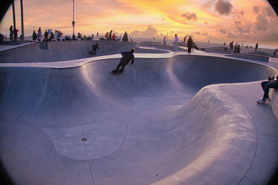 High angle view of people walking on beach against sky during sunset