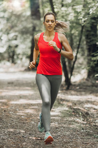 Full length of female athlete running in forest