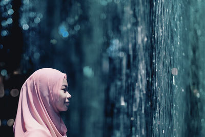 Side view of teenage girl looking at artificial waterfall