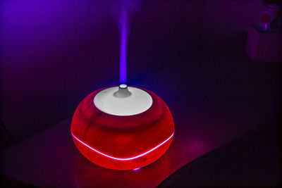 Close-up of illuminated electric lamp with smoke on table