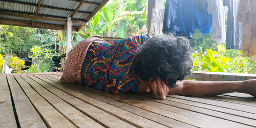 Senior woman sleeping on floorboard