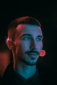 Close-up portrait of young man against black background