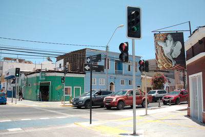 Cars on road by buildings against sky in city