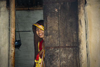 Portrait of a smiling young woman standing against wall