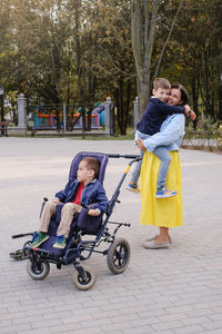 Family with cerebral palsy child on special wheelchair walking outdoors. integration and
