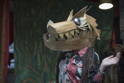 Portrait of young female artist wearing a dragon mask
