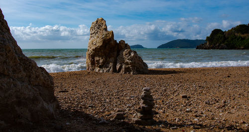 Rock formation on beach against sky