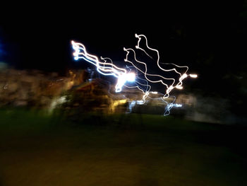 Light trails in city against sky at night