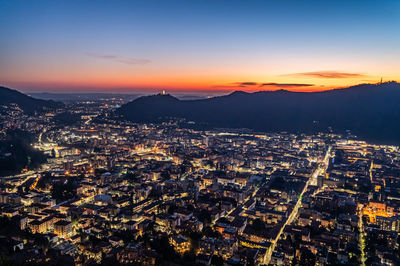 The city of como, by evening, with the lights, the hills and castel baradello.