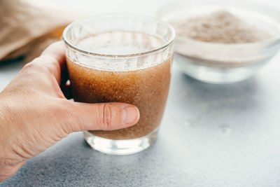 Close-up of hand holding drink on table