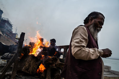 People taking heat from a dead body burning. you can see just the feet in the fire.