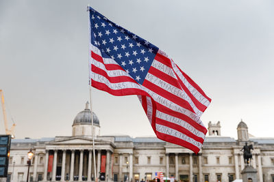 Low angle view of flag against sky in city