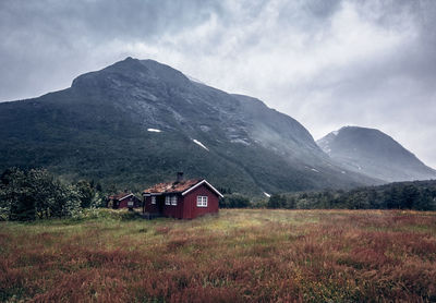 House on field by mountains against sky
