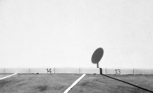 Shadow of person on road against wall