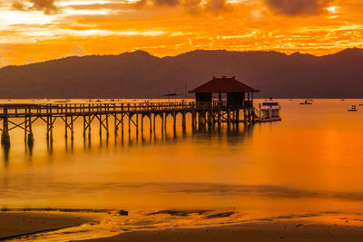 A wooden pier stretches out into a calm bay at sunset, near trenggalek, east java, indonesia.