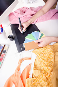 Midsection of woman with color swatches using graphics tablet on table