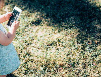 Midsection of woman photographing with mobile phone