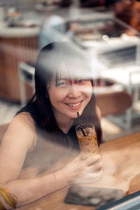 Portrait of a smiling young woman sitting on table