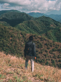 Rear view of man standing on mountain against sky