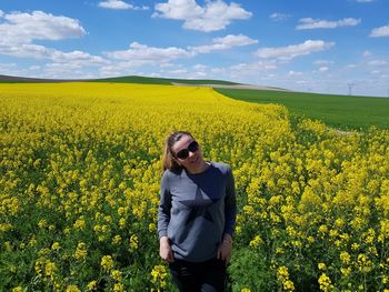 Woman standing amidst oilseed rape