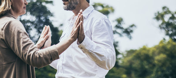 Midsection of couple standing against trees