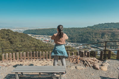 Full length of woman standing on mountain against clear sky