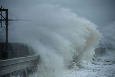 Waves splashing on shore against sky