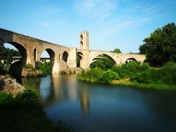 Arch bridge over river against sky