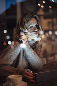 Portrait of woman sitting in illuminated room