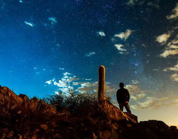 Low angle view of woman standing on rock against sky